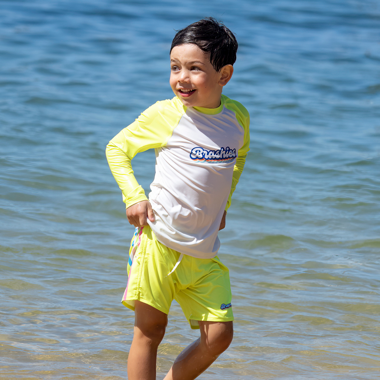 Child in Palm Beach yellow rashie swimming in shallow water